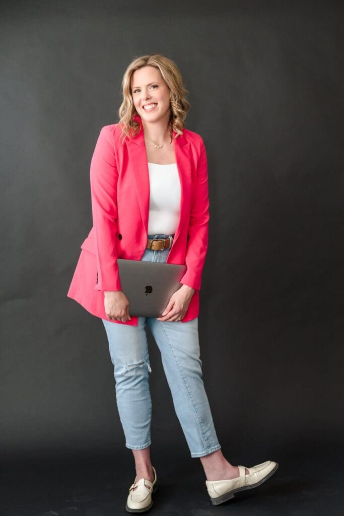Woman entrepreneur in a bold pink blazer and black background for studio headshot