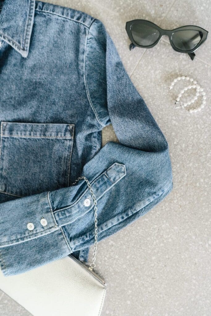 Jean top laid out with accessories, sunglasses purse and earrings for Kelowna brand shoot