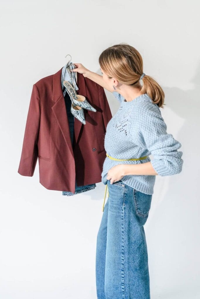 Woman planning brand photoshoot outfits with a statement burgundy blazer
